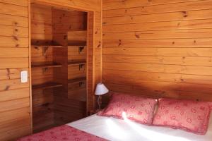 a bedroom with wooden walls and a bed with pink pillows at Los Condores Bariloche in San Carlos de Bariloche