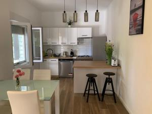 a kitchen with white cabinets and a glass table and stools at Apartment 877-3 in Bibinje