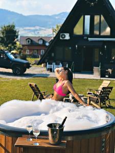 a woman sitting in a hot tub with two wine glasses at Cabana A Toplita in Topliţa