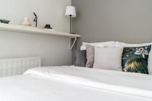 1 dormitorio con 1 cama con sábanas y almohadas blancas en Roost Laivasto 12, en Helsinki