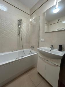 La salle de bains est pourvue d'une baignoire, d'un lavabo et d'une douche. dans l'établissement Apartament Sky, à Leszno