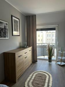 - une chambre avec une commode et une grande fenêtre dans l'établissement Apartament Sky, à Leszno