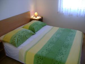 una cama con sábanas verdes y amarillas y una lámpara sobre una mesa en Apartments house Mai with pool Poreč, en Poreč