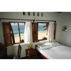 Karikkathi Beach House في تريفاندروم: سريرين في غرفة مطلة على الشاطئ