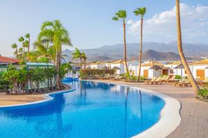 einen Pool in einem Resort mit Palmen und Häusern in der Unterkunft Royal Tenerife Country Club in San Miguel de Abona