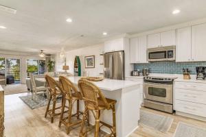 ペンサコーラにあるWalk to Florabama from Renovated Ground Floor 2Bd-2Ba with Pickleball, Boat Slipsの白いキャビネットとテーブルと椅子のあるキッチン +57枚の写真