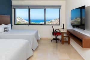 a bedroom with two beds and a desk and a television at Gamma Los Cabos in San José del Cabo