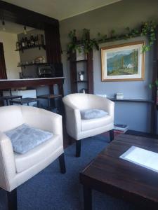 sala de estar con 2 sillas blancas y mesa en ROCAYAS HOME en Esquel