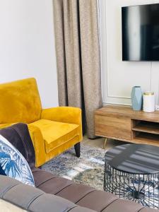 a living room with a yellow chair and a tv at Mayswood Self Catering Apartments in Gaborone