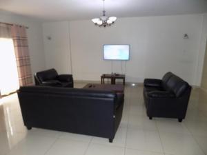 a living room with two black leather couches and a tv at Comfort Silverline Apartments in Kampala