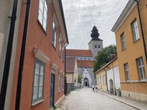 a person walking down a cobblestone street with a church at Mysig innerstads lägenhet in Visby