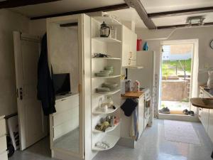 a kitchen with white shelves and a window at Mysig innerstads lägenhet in Visby +7 photos
