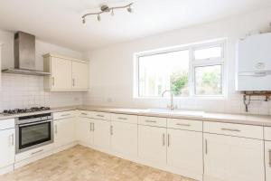 een witte keuken met witte kasten en een raam bij Surrey - Private House with Garden & Parking 12 in Wentworth