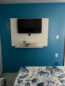 ein Schlafzimmer mit einem TV an einer blauen Wand in der Unterkunft CASA DE PRAIA PEROBA in Maragogi