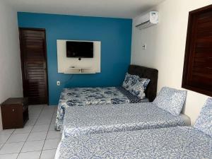 Zimmer mit 2 Betten und einem TV an der Wand in der Unterkunft CASA DE PRAIA PEROBA in Maragogi
