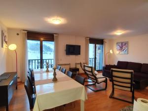 een woonkamer met een tafel en stoelen en een bank bij Apartamentos Grifo Vacances Julia in El Tarter