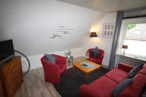 a living room with two red chairs and a tv at Nord-Strand in Norden