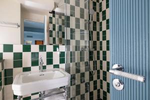 a bathroom with a sink and green and white tiles at Hôtel La Conversation in Paris