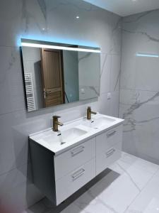 La salle de bains est pourvue d'un lavabo blanc et d'un miroir. dans l'établissement VILLA LENA, à Sainte-Geneviève-des-Bois