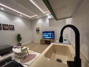 Il dispose d'une cuisine avec un évier et d'un salon avec une télévision. dans l'établissement شقة luxury في شمال الرياض الصحافة, à Riyad