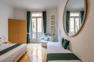 パリにあるPrestigious Appartement Trocaderoのベッド2台と鏡が備わるホテルルームです。