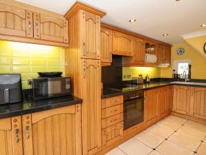 uma cozinha com armários de madeira e bancadas pretas em Chapel House em Brough