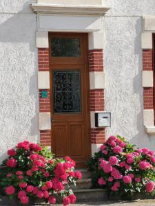 Una puerta de una casa con flores delante en La maison aux rosiers en Montmarault