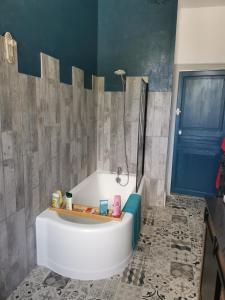 baño con bañera y puerta azul en La maison aux rosiers, en Montmarault