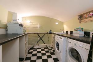 een wasruimte met een wasmachine en een geruite vloer bij The Notting Hill Residence - 2 BR Apartment Close to Hyde Park in Londen