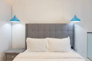 Duas luzes azuis por cima de uma cama com almofadas brancas em Skyline 1 Bed, Loft 2 @Embassy Gardens em Cantonments