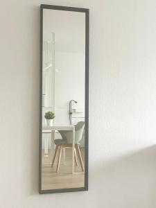 een spiegel aan een muur met een tafel en een stoel bij Modern und Renoviert in Neurenberg