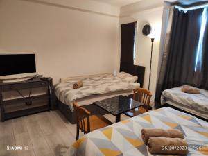 Habitación con 2 camas y mesa con TV. en St Lucia lodge Leicester long stays available en Leicester