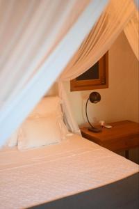 a bedroom with a white bed and a desk with a lamp at Pausa Trancoso in Trancoso
