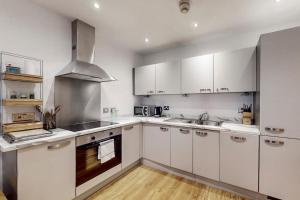 a kitchen with white cabinets and a stove top oven at Bright & beautiful 1 bedroom flat in London Bridge in London