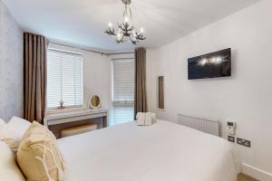 Un dormitorio con una gran cama blanca y una lámpara de araña. en Bright & beautiful 1 bedroom flat in London Bridge, en Londres