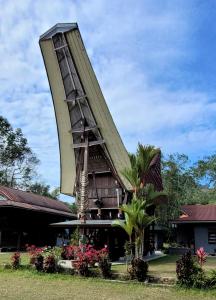 a building with a triangular roof with flowers in front at Toraja Homestay & Coffee Bunna in Rantepao