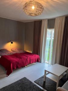 um quarto com uma cama com um cobertor vermelho em Lägenhet med sjötomt. Vildmark i tätort. em Umeå