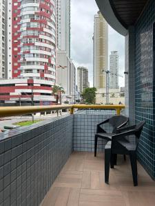 a balcony with a black chair and a view of a city at Pousada Villa Atlântica in Balneário Camboriú