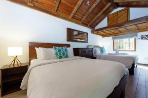 two beds in a bedroom with wooden ceilings at Hotel Rip Jack Inn in Playa Grande
