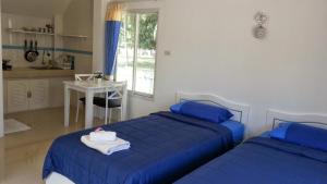 a bedroom with two beds with blue sheets and a table at Vipha Ville Resort in Ban Huai Yang