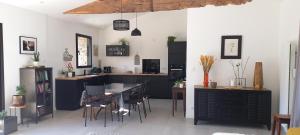 a kitchen with black cabinets and a table and chairs at La villa du pressoir, classé 3 étoiles meublé de tourisme in Le Pallet