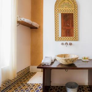 Hotel Blanco Riad في تطوان: حمام مع حوض ومرآة