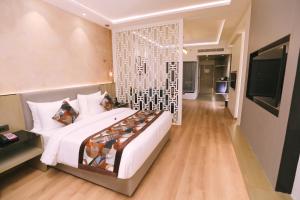 a bedroom with a large white bed and a television at Regenta Place Amritsar by Royal Orchid Hotels Limited in Amritsar