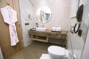 a bathroom with a sink and a toilet and a mirror at Regenta Place Amritsar by Royal Orchid Hotels Limited in Amritsar