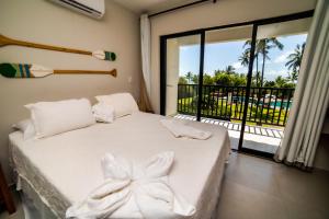 um quarto com uma cama branca e uma grande janela em Vivant Eco Beach OFICIAL em Barra Grande