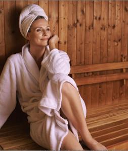 a woman in a towel sitting in a sauna at Cozy house with sauna 10 min walk to Santa Claus Village in Rovaniemi