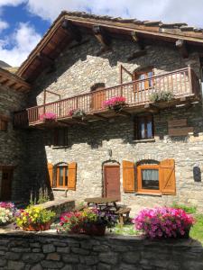 kamienny dom z balkonem i kwiatami przed nim w obiekcie Chalet 3 Céline 6 personnes Vieux Village w mieście Bonneval-sur-Arc