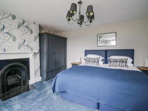 a bedroom with a blue bed and a fireplace at The Hollies in Carlisle
