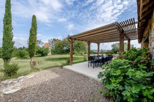 a wooden pergola with a table and chairs under it at Gîte lOragée Les Farguettes in Cadouin