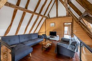 a living room with a blue couch and a tv at Gîte lOragée Les Farguettes in Cadouin